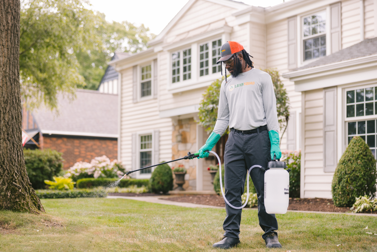 A man spraying the perimeter of a house