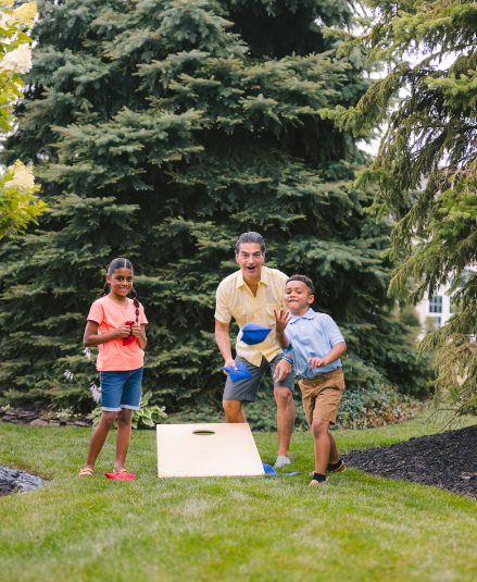 man playing yard games with who children